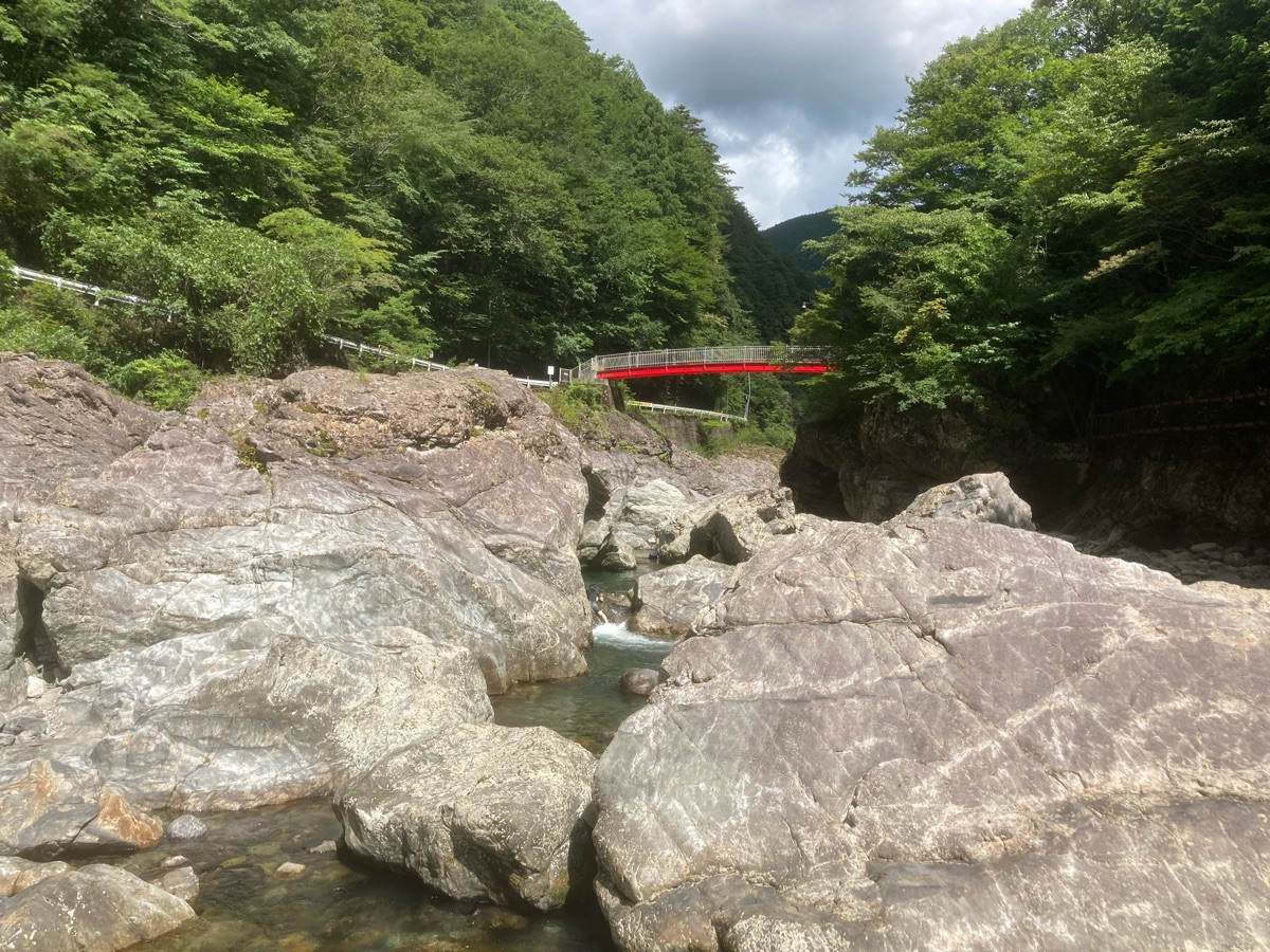 岩場の向こうに赤い橋が見える渓谷